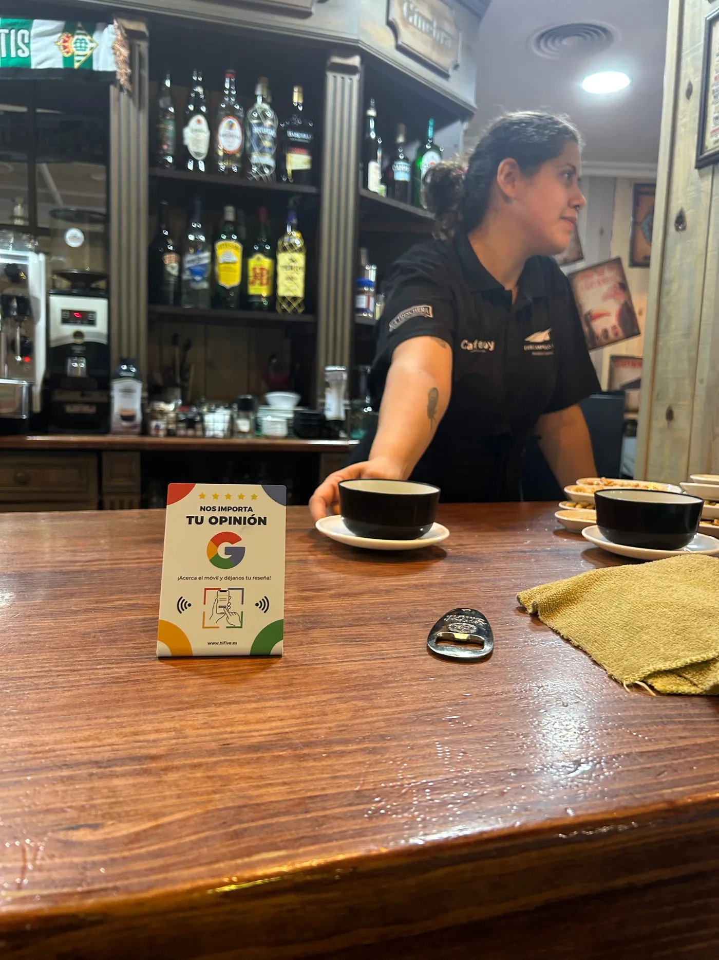 Expositor en la barra de una cafetería, junto a dos cafés